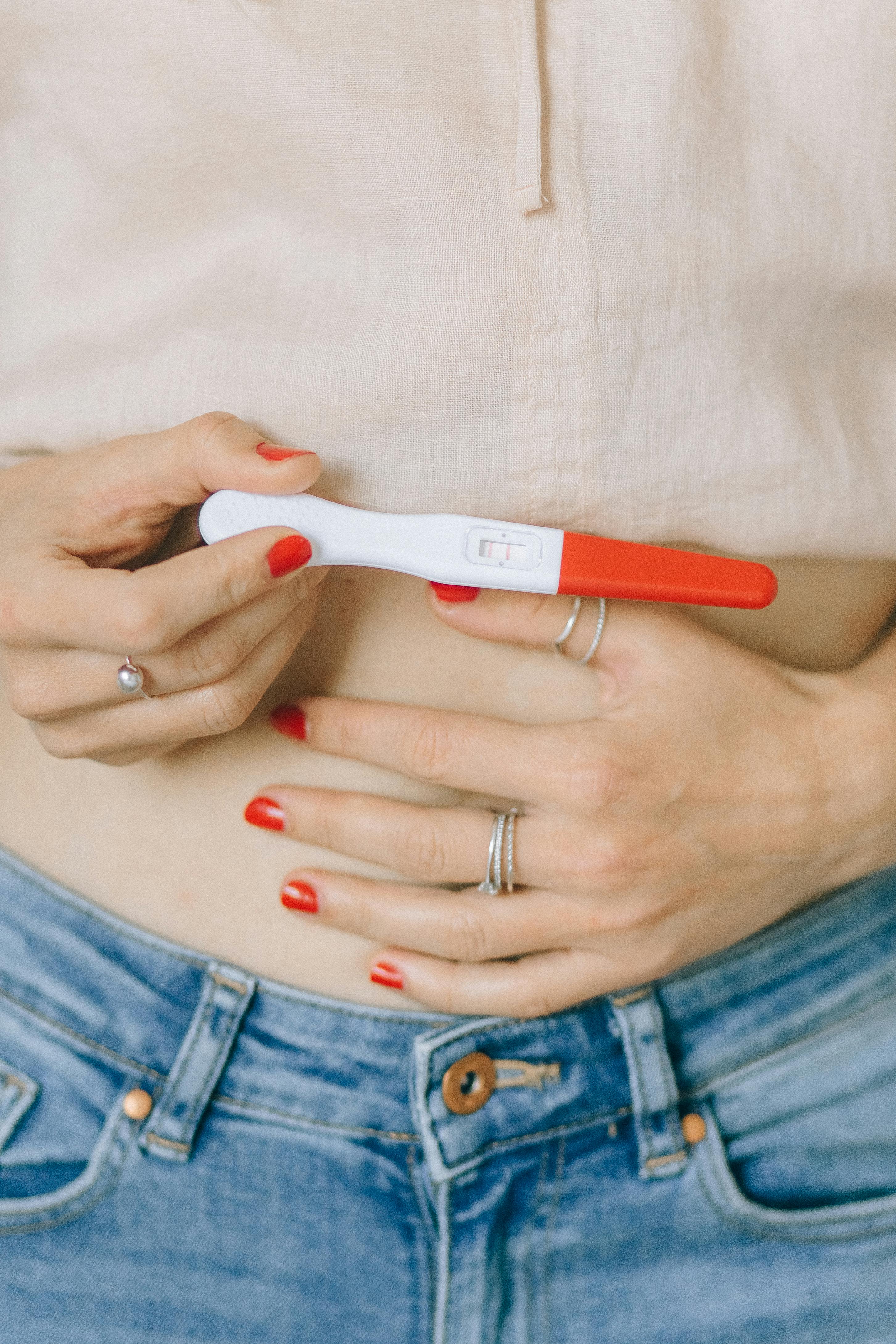 individual touching their stomach and holding pregnancy test