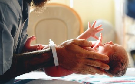 man holding newborn over scales