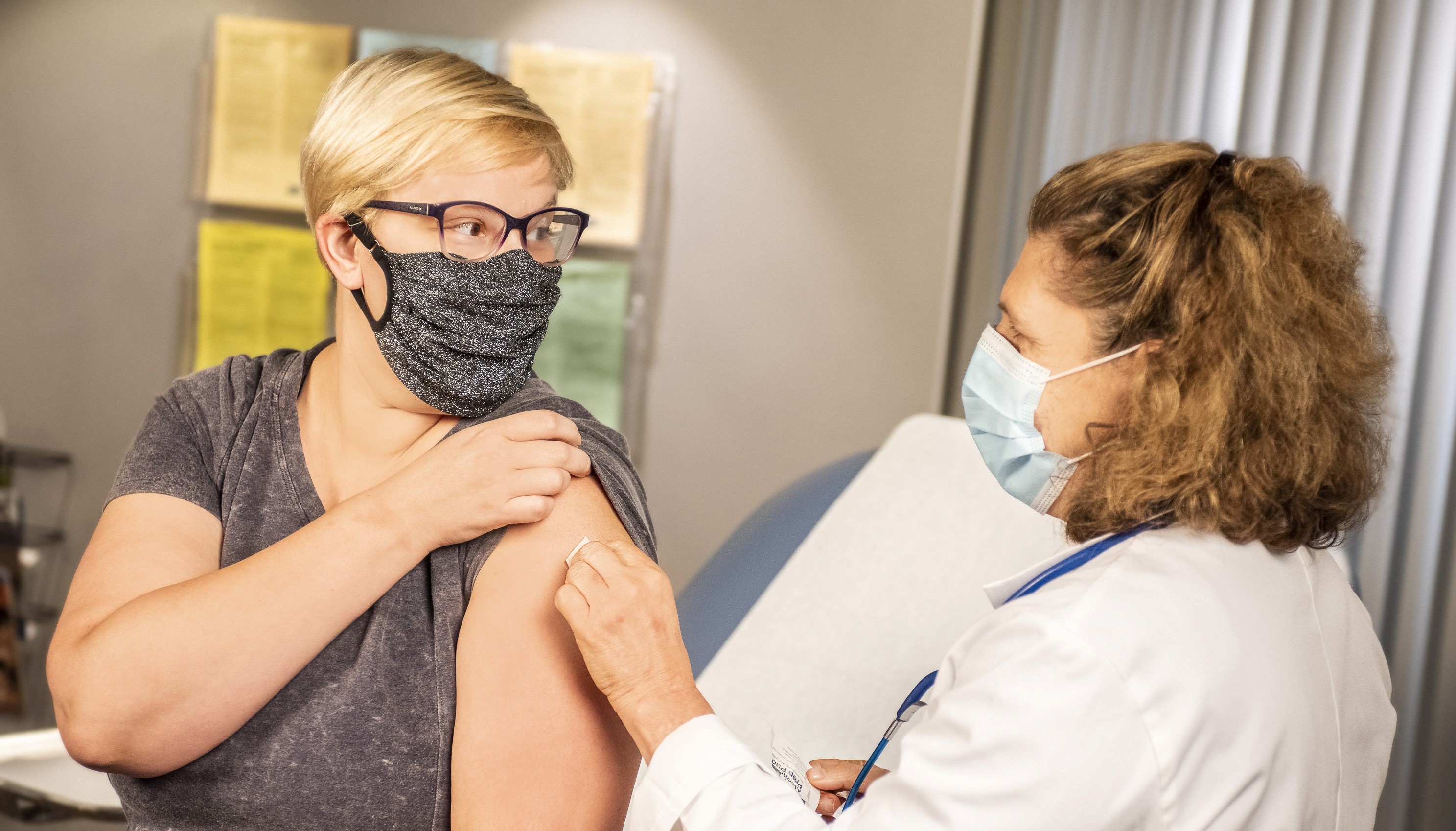 Woman touching band aid on arm after vaccination
