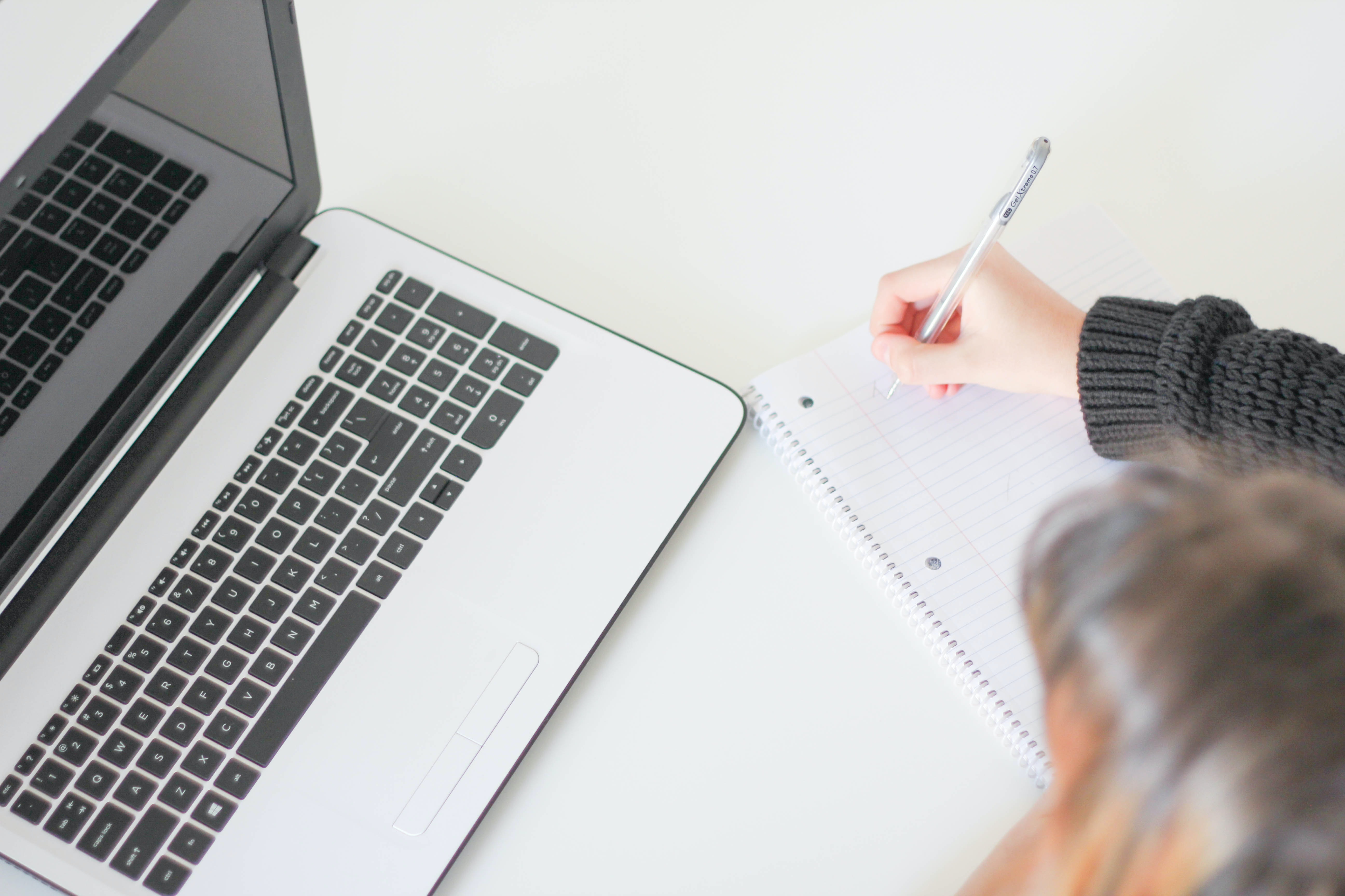 woman with a stethoscope next to her typing on laptop