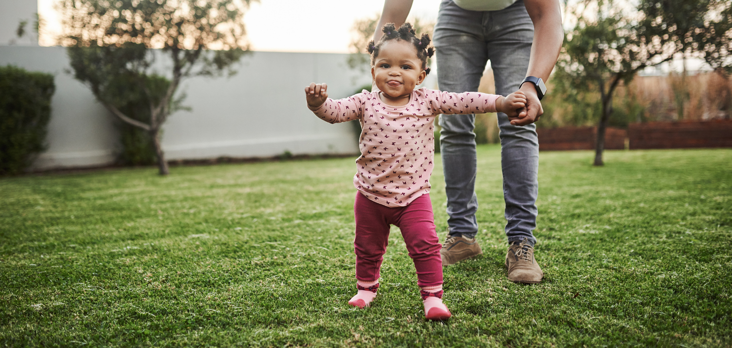 Une bambine fait ses premiers pas dans la pelouse