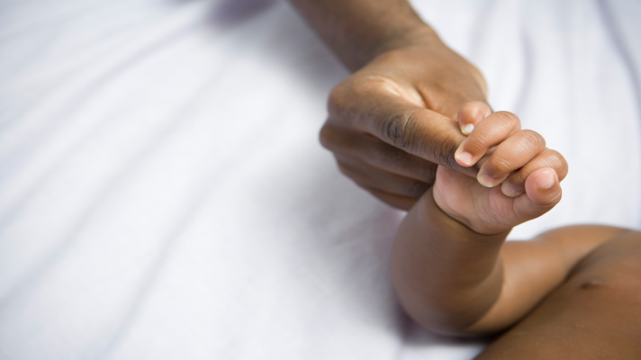woman and baby holding hands (only shows arms and hands)