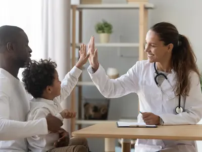 A child sitting on parent's lap giving high-five to another parent